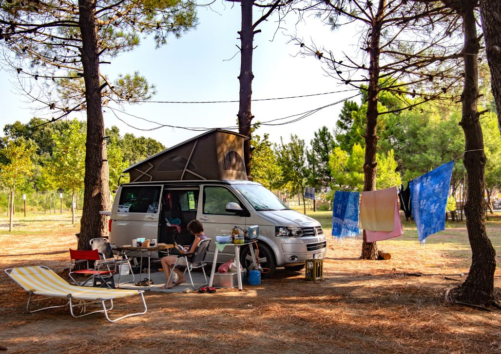 Žena sedi pored svog kampera i kampuje u šumi pored mora kod Ulcinja u Crnoj Gori.