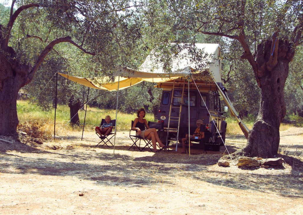 Žena i dva dečaka sede u hladu kod svog kampa u maslinjaku u Crnoj Gori.