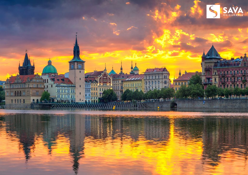 Panoramski pogled na grad Prag pri zalasku sunca sa značajnim arhitektonskim obeležjima i refleksijom u Vltavi, simbolom češke kulture i istorije.