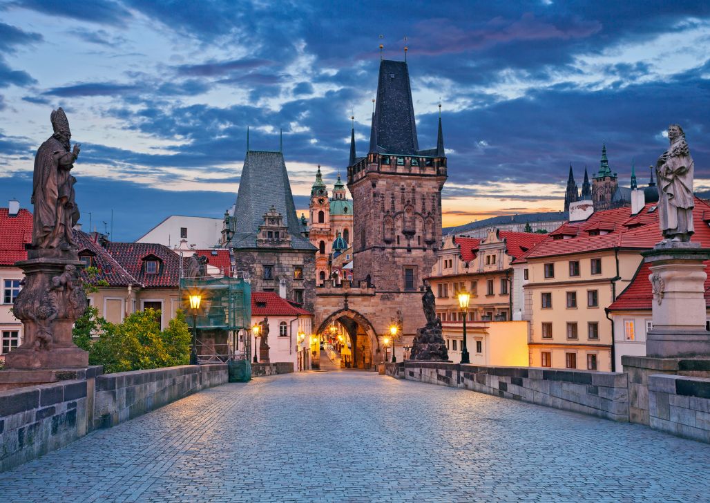 Svetlost zore osvetljava Karlov most i kipove u Pragu, pružajući magičan pogled na Stari grad u tišini svitanja.