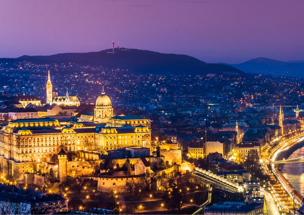 Budimski dvorac osvetljen noću sa panoramom Budimpešte.