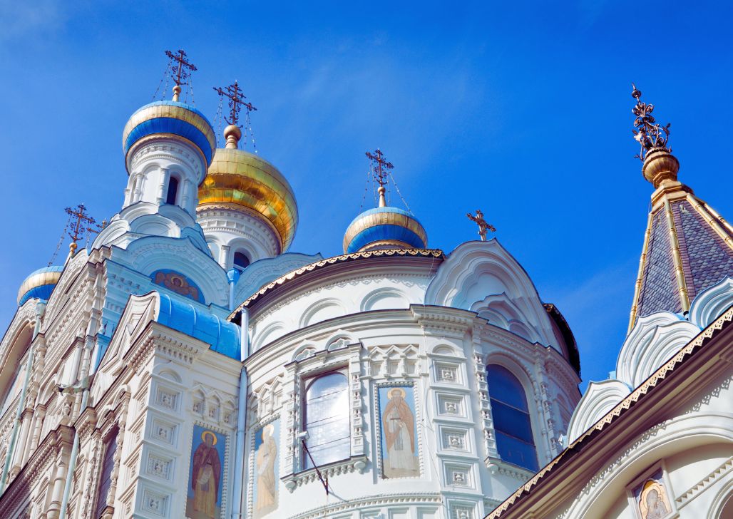 Zlatne kupole i plavo-bijela fasada Crkve Svetog Petra i Pavla u Karlovim Varima pod plavim nebom.