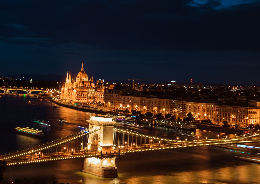 Panorama Budimpeštanskog parlamenta i Lančanog mosta u noći, reka Dunav sa brodovima.