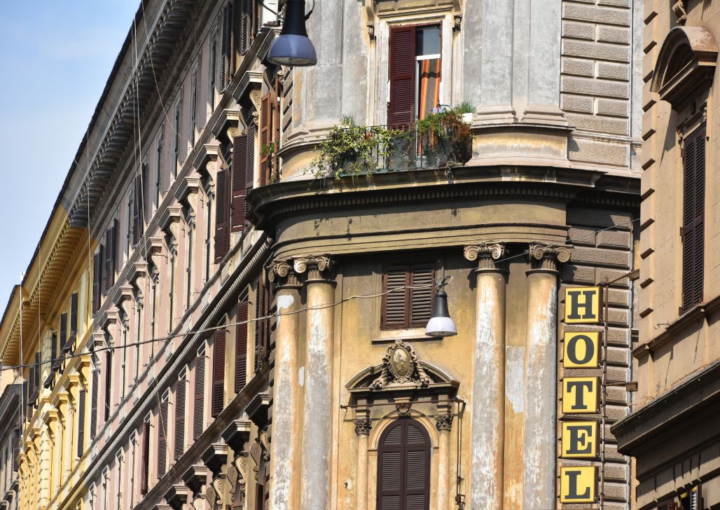 Ugao zgrade sa klasičnom arhitekturom i natpisom "Hotel" na fasadi u rimskoj četvrti.
