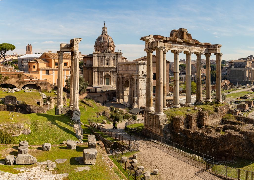 Ruševine Rimskog Foruma sa savremenim Rimom u pozadini.