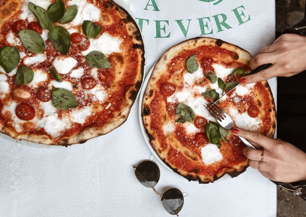 Dve osobe jedu autentičnu italijansku pizzu na ulicama Rima