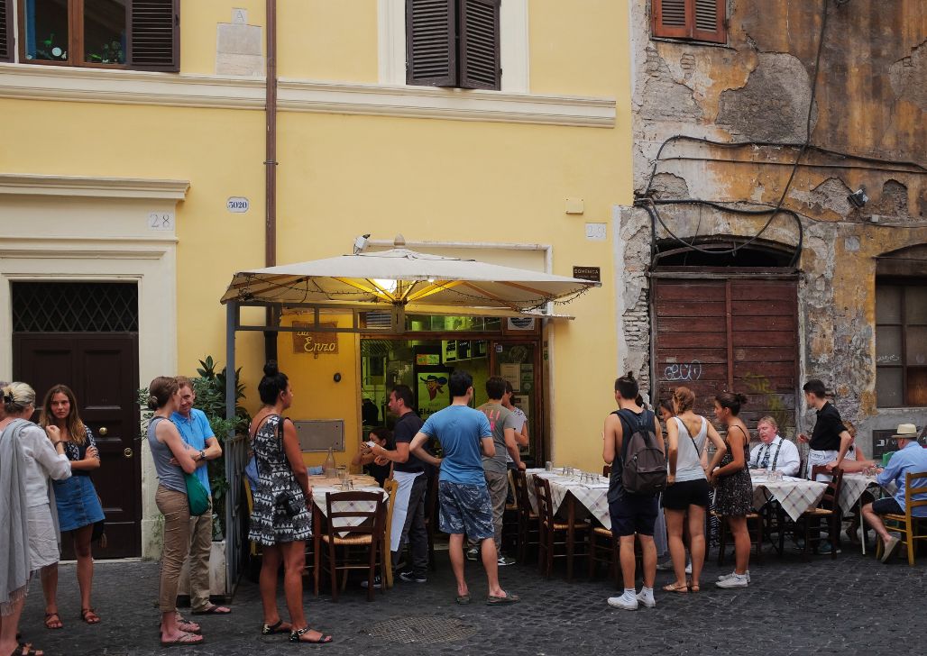 Ljudi uživaju u jelu na otvorenom u restoranu Da Enzo al 29 u Rimu